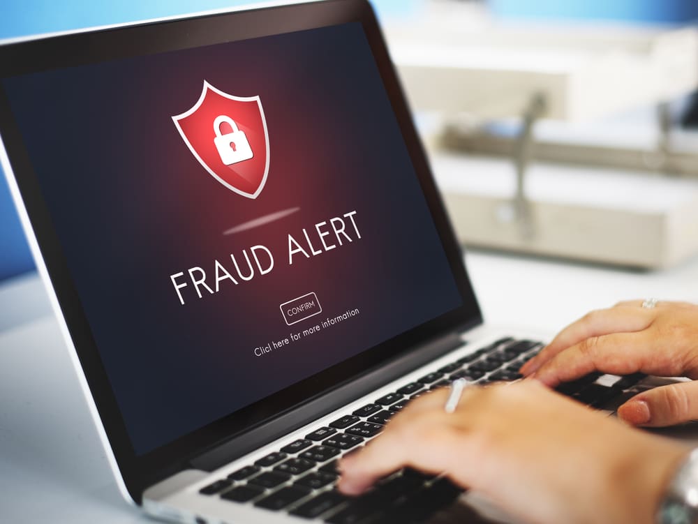 FRAUD ALERT graphic on a laptop screen