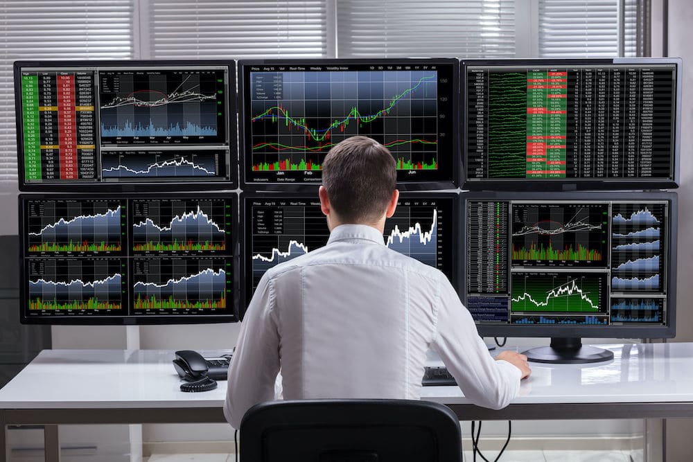 Man sitting at desk with loads of graphs and charts 