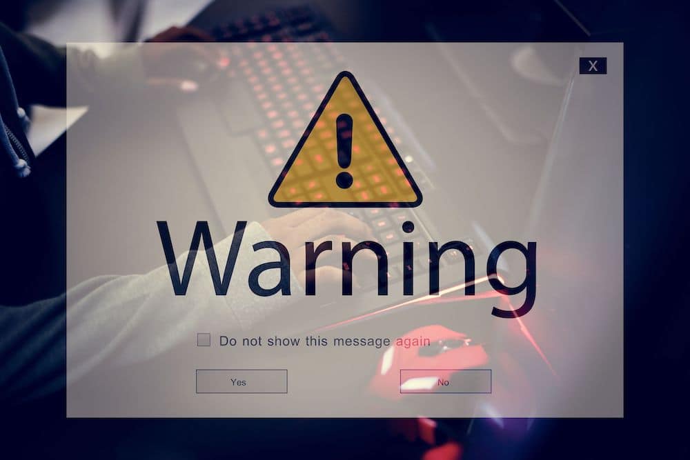 Stock image of a Computer warning edited over someone using their laptop