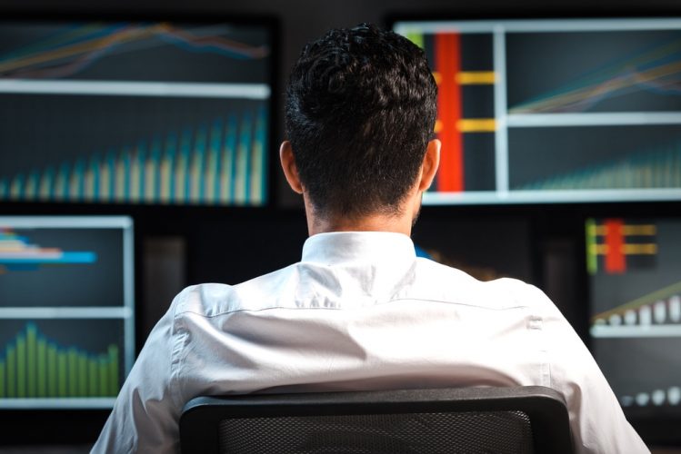 Man sitting in front of screens with data on it
