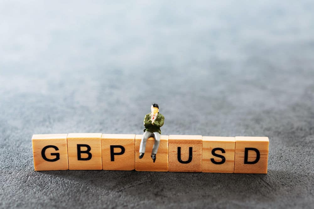 Toy Man sitting on top of toy blocks reading GBPUSD