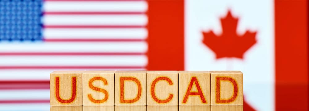 Toy blocks reading USDCAD in front of the USA and Canada flags