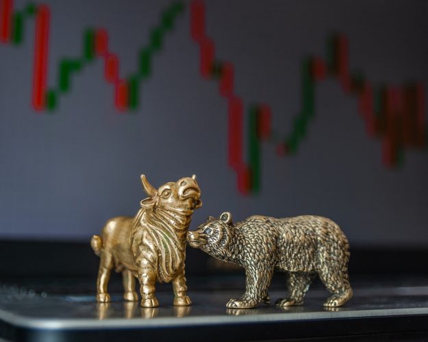 Bear and Bull statuettes in front of a Stock Price graph
