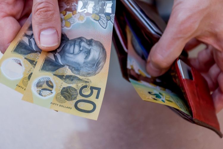 Someone putting Australian 50 Dollar Bills in their wallet 