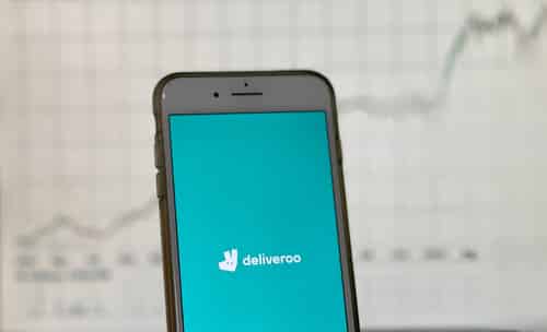 Deliveroo App Welcome Screen in front of Stock Chart