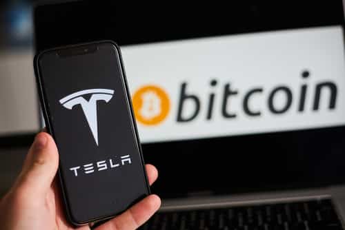 Tesla Logo on Smartphone in Front of Bitcoin Logo