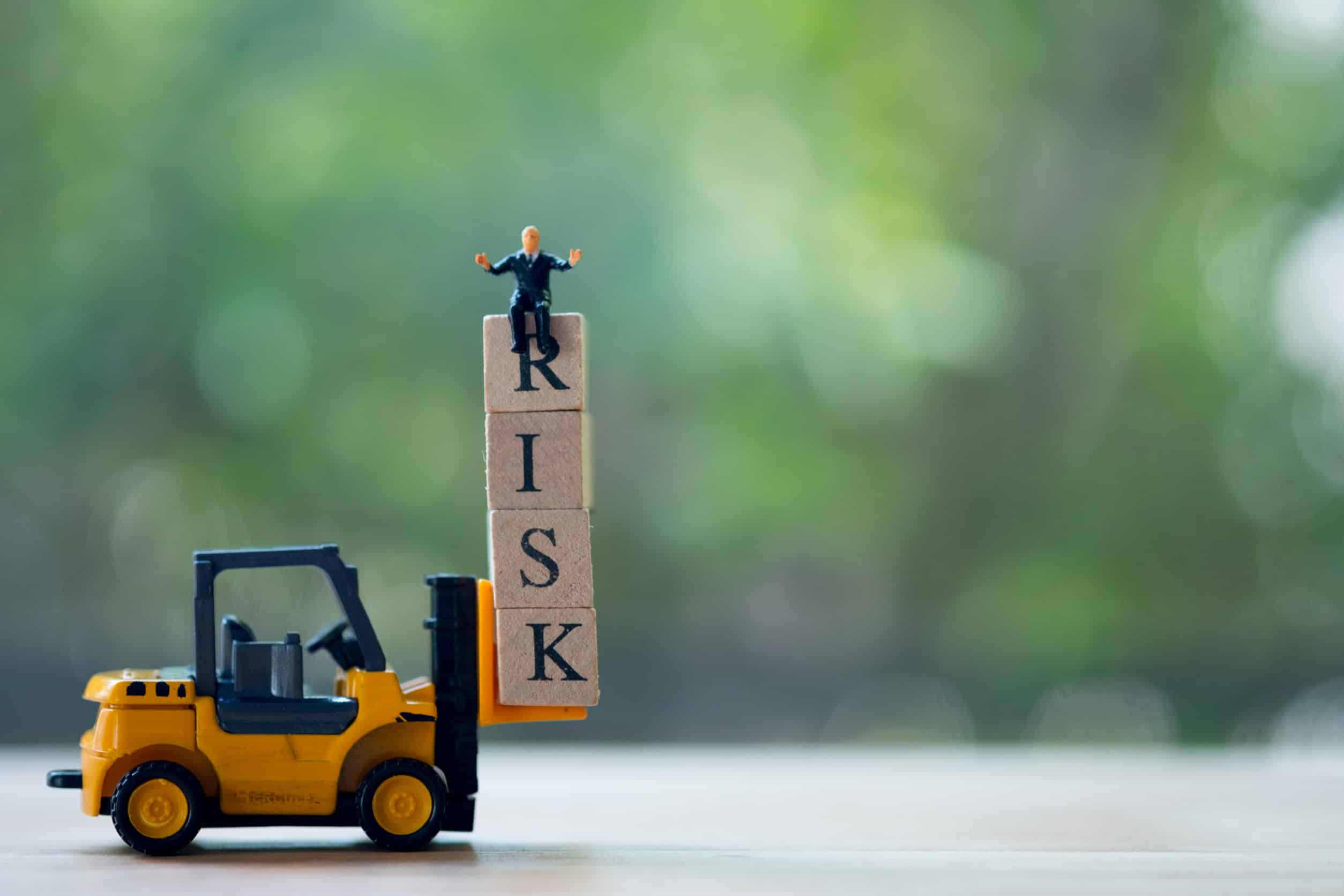 Toy Blocks which read RISK, with a toy crane and toy man 